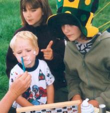 Small boy being poked in ear while getting 
toothpaste smeared across his face